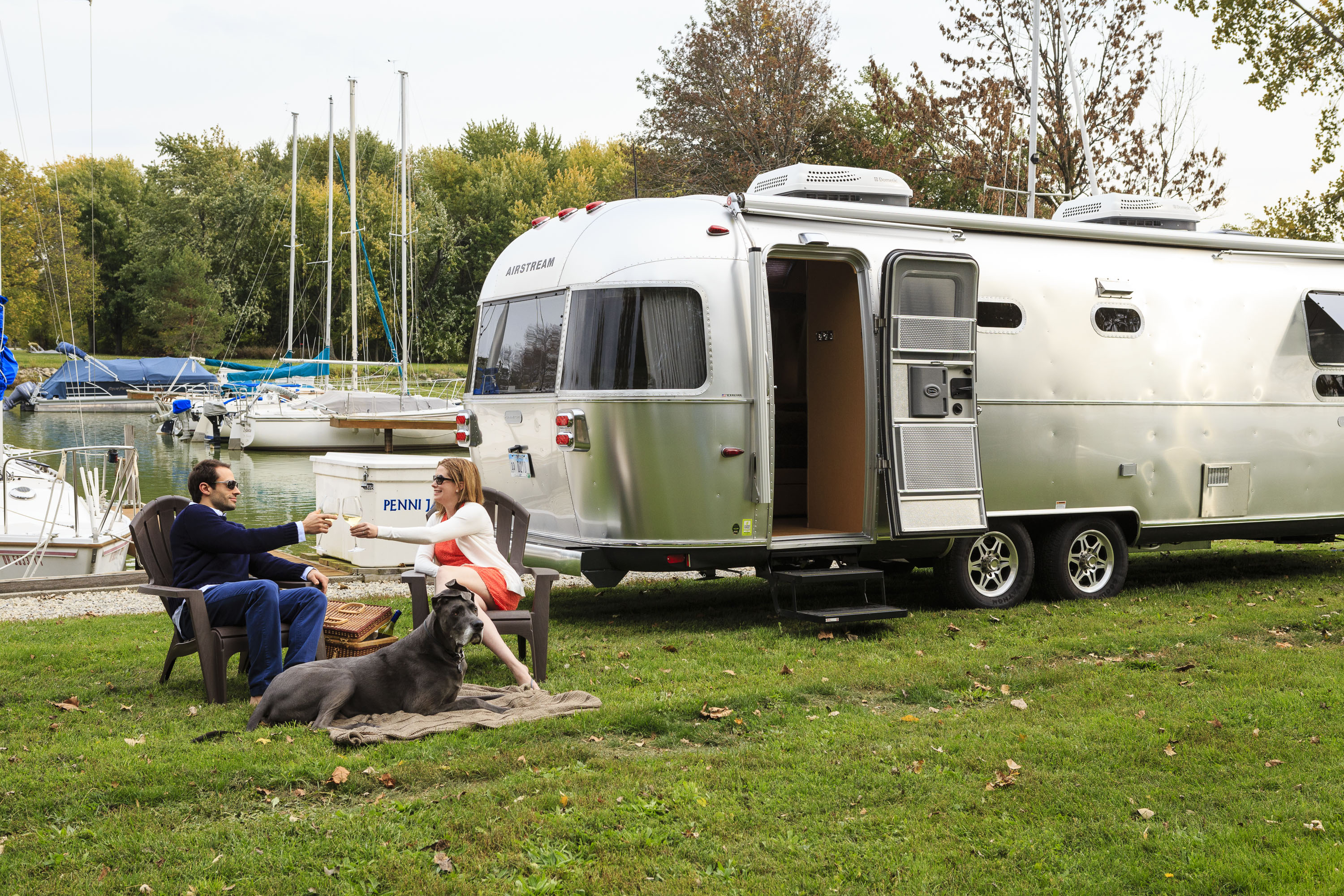 Airstream camper and couple with a dog by the lake